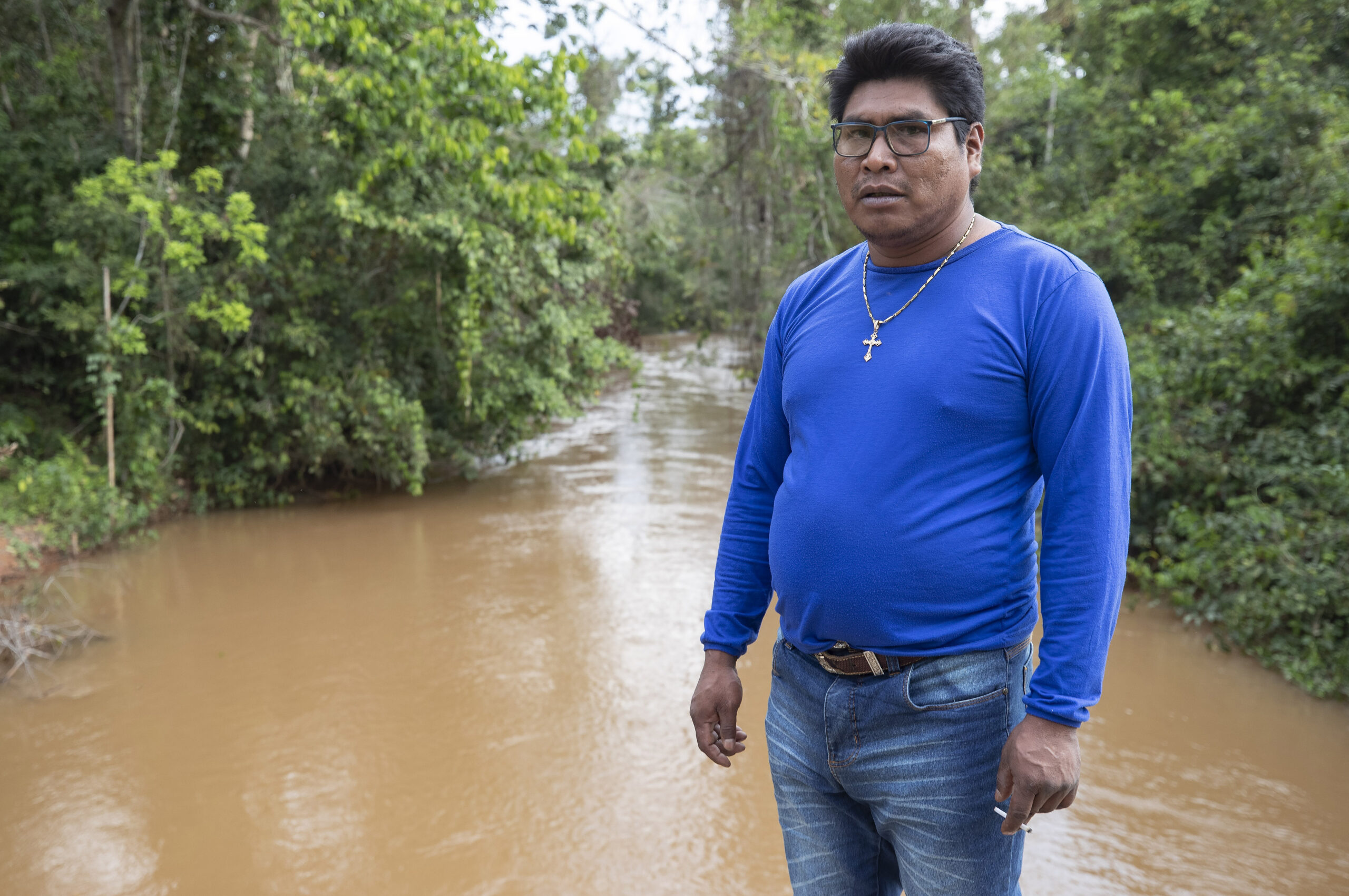 In this Aug. 26, 2019 photo, indigenous leader Saulo Katitaurlu stands next to the Sarare River, in the southwestern Amazon near Conquista D'Oeste, in the Brazilian state Mato Grosso. “Many years ago, the water wasn’t like this,” he told AP journalists, saying increased cattle ranching and soy farming have made muddied the once clear waters. Image by AP Photo/Andre Penner.
