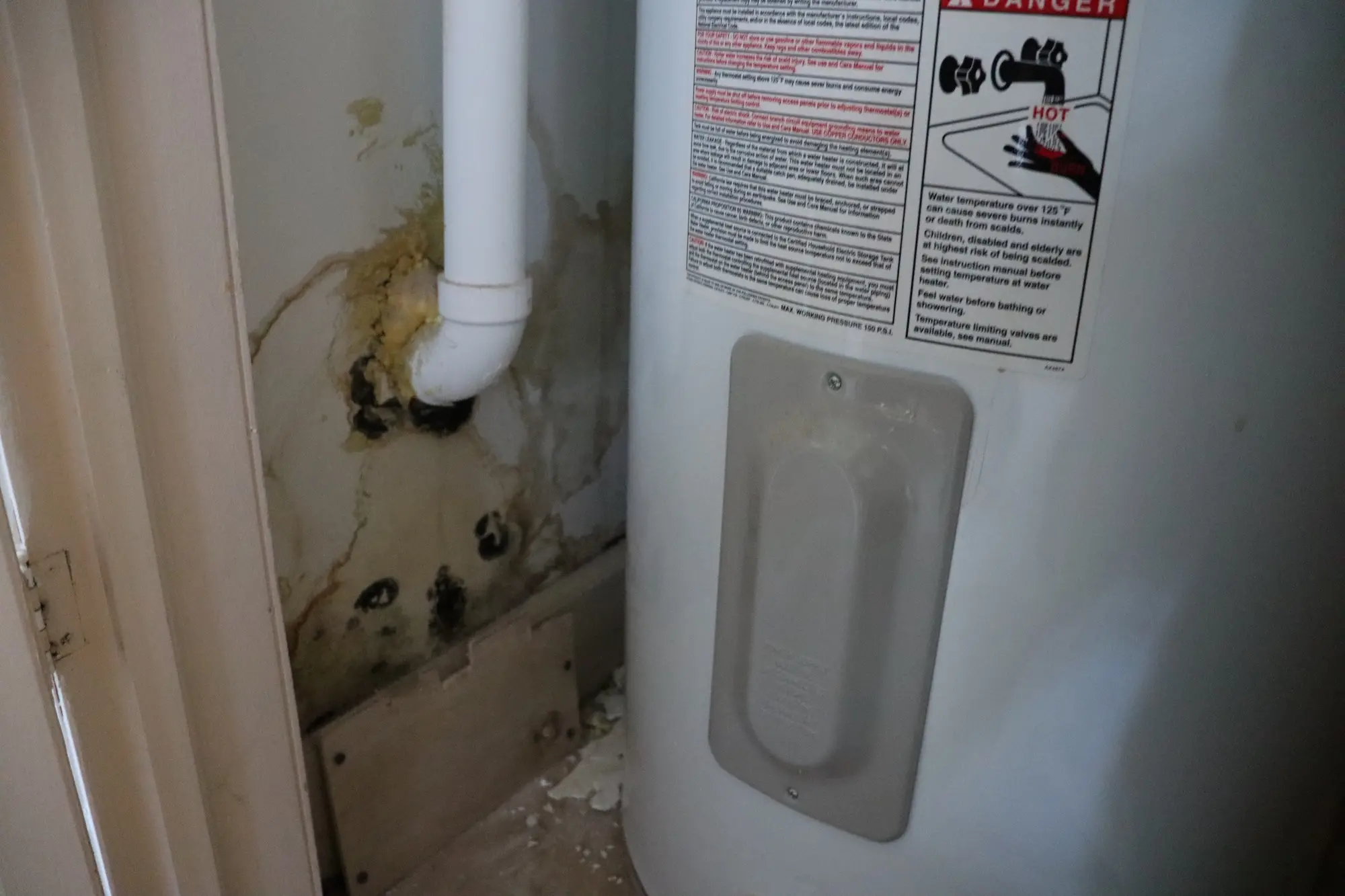 a water heater with stains near a pipe attachment to a wall