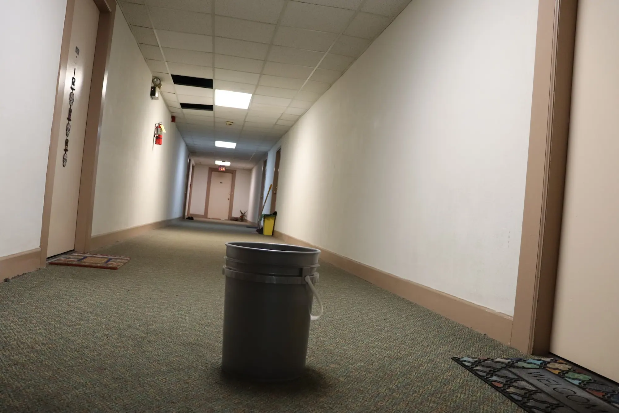 A hallway with a bucket to catch leaks