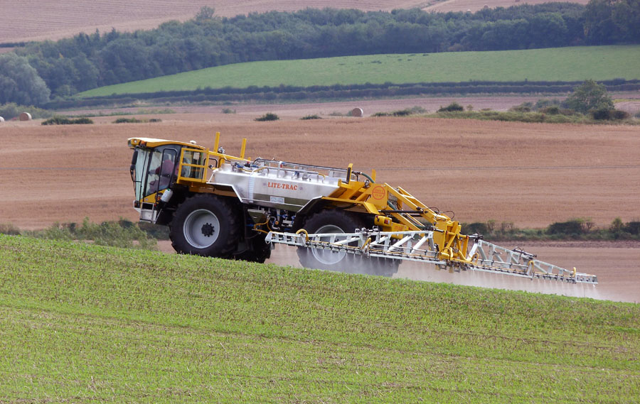 A self-propelled crop sprayer applies pesticide to a field.