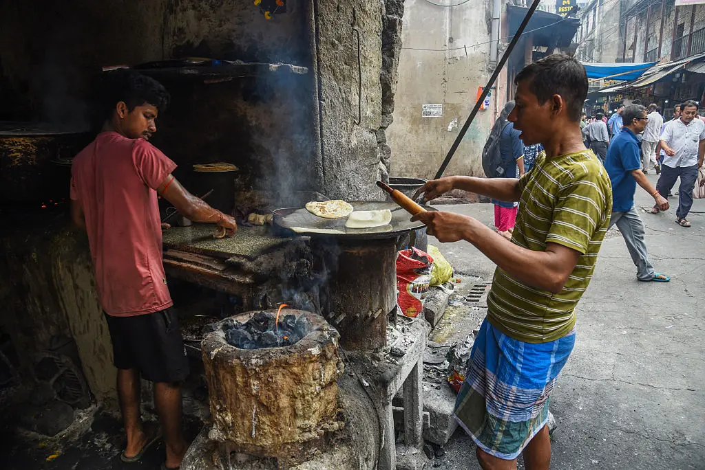 Two men making street food using coal for fuel