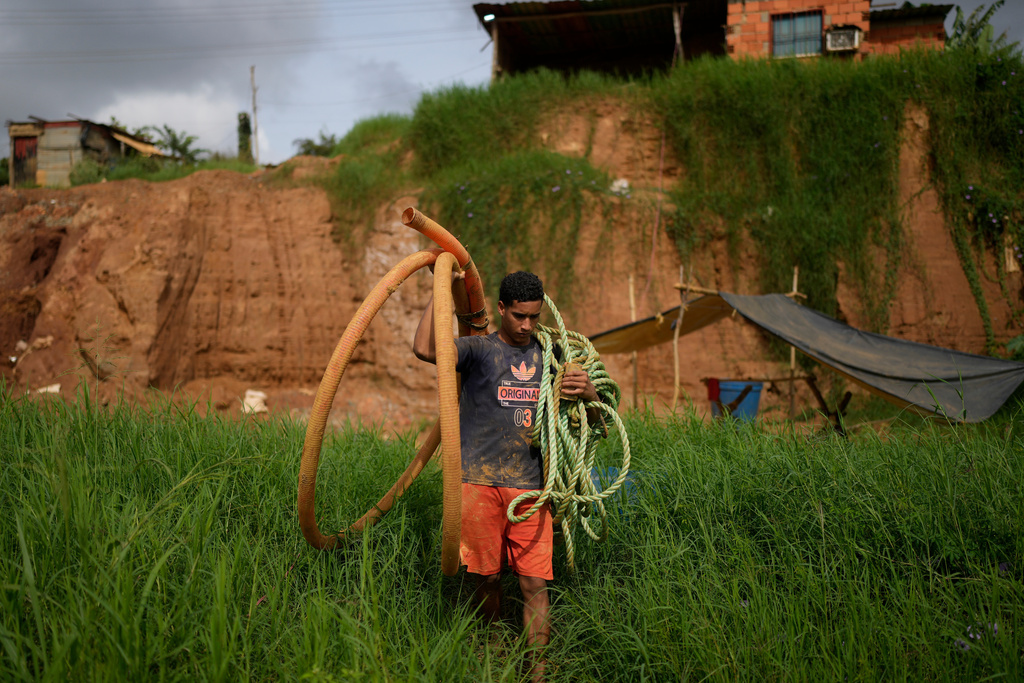 A miner carries a hose to a gold mine in El Callao, Venezuela. (AP Photo/Matias Delacroix)