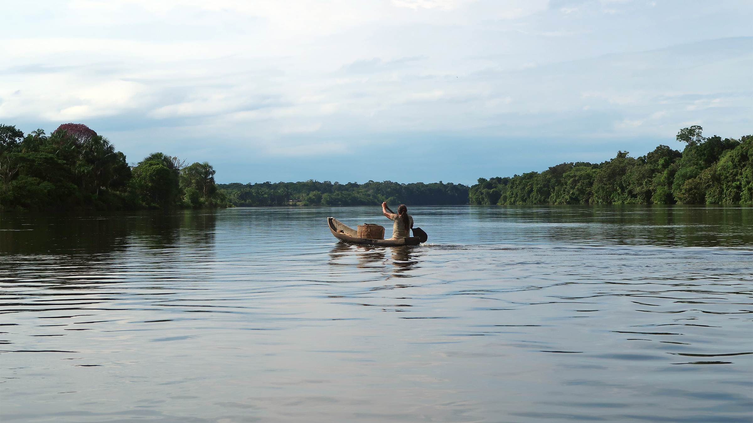 A woman from the Indigenous Macaquiño community in Vaupés pushes her boat across the Vaupés River towards her traditional forest garden, or chagra. Image by Aimee Gabay/Mongabay.