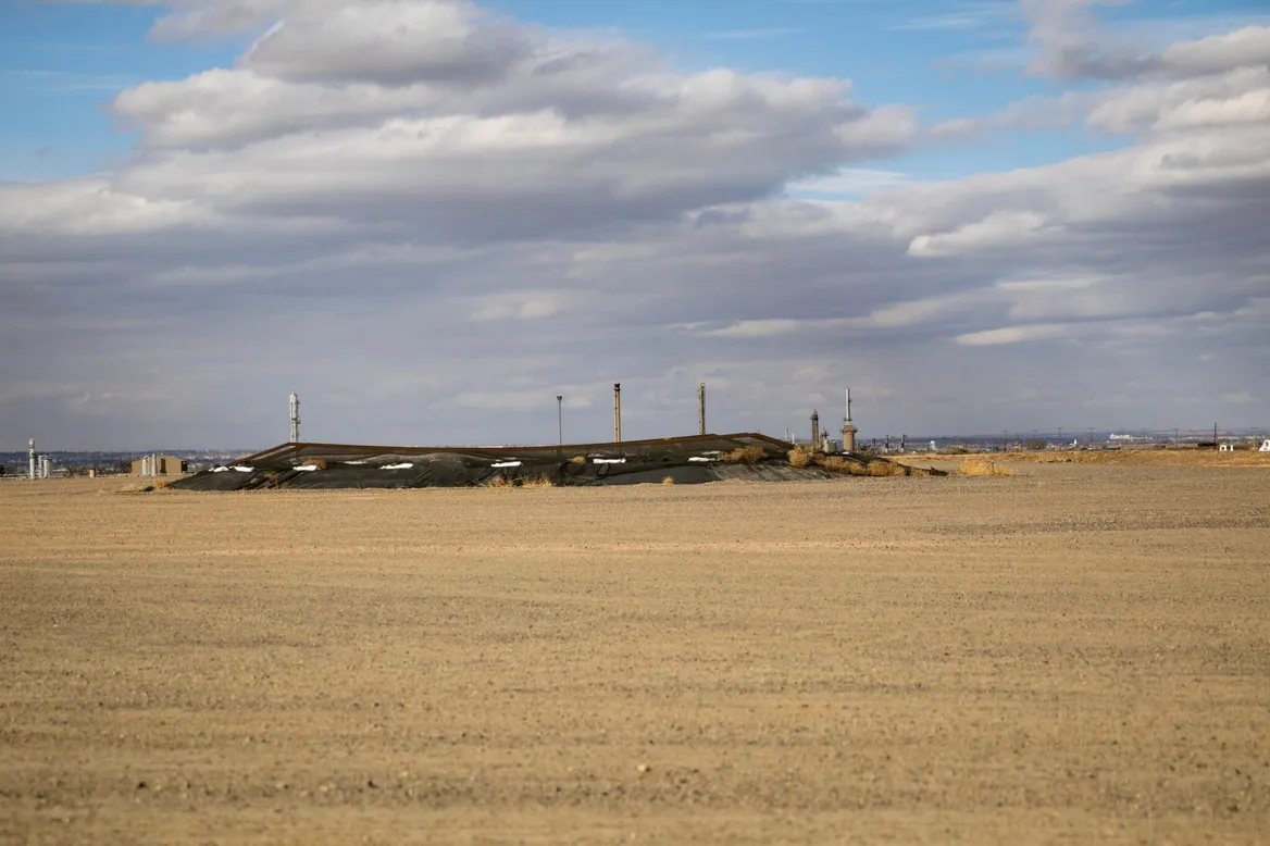 Field with a slightly raised area in the center circled by some drilling rigs