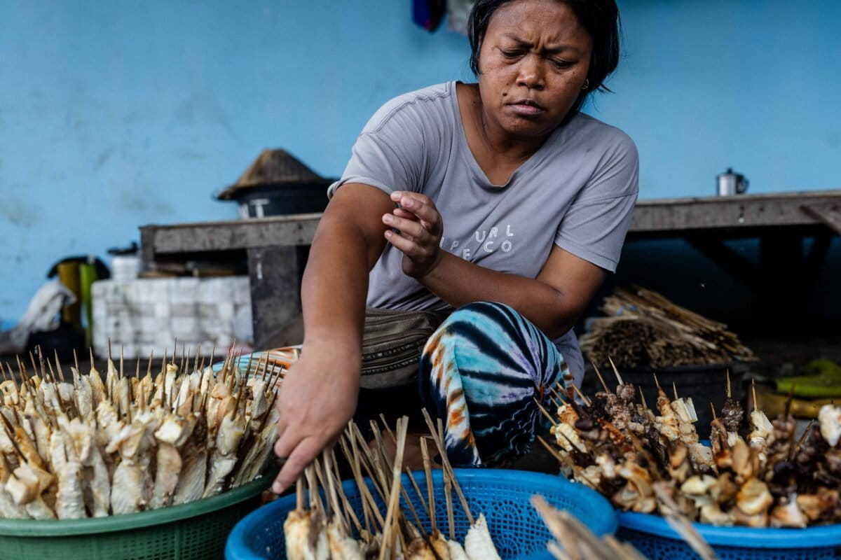 A woman prepares shark satay for public consumption at a warehouse in Rumbuk village