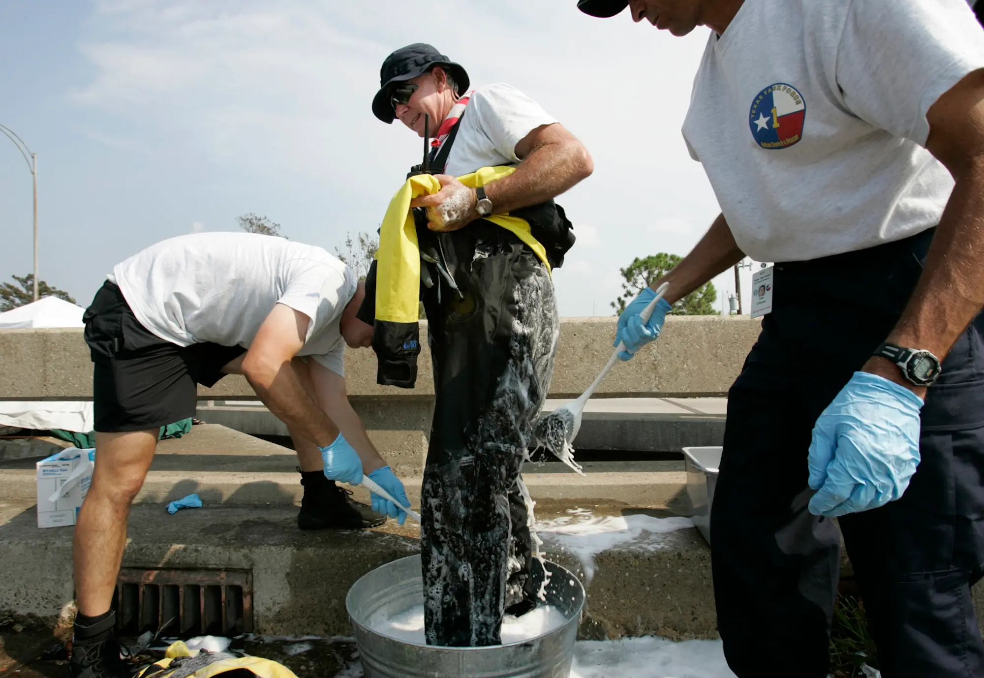 a man is washed down with disinfectant by people in official t-shirts with logos resembling the texas state flag