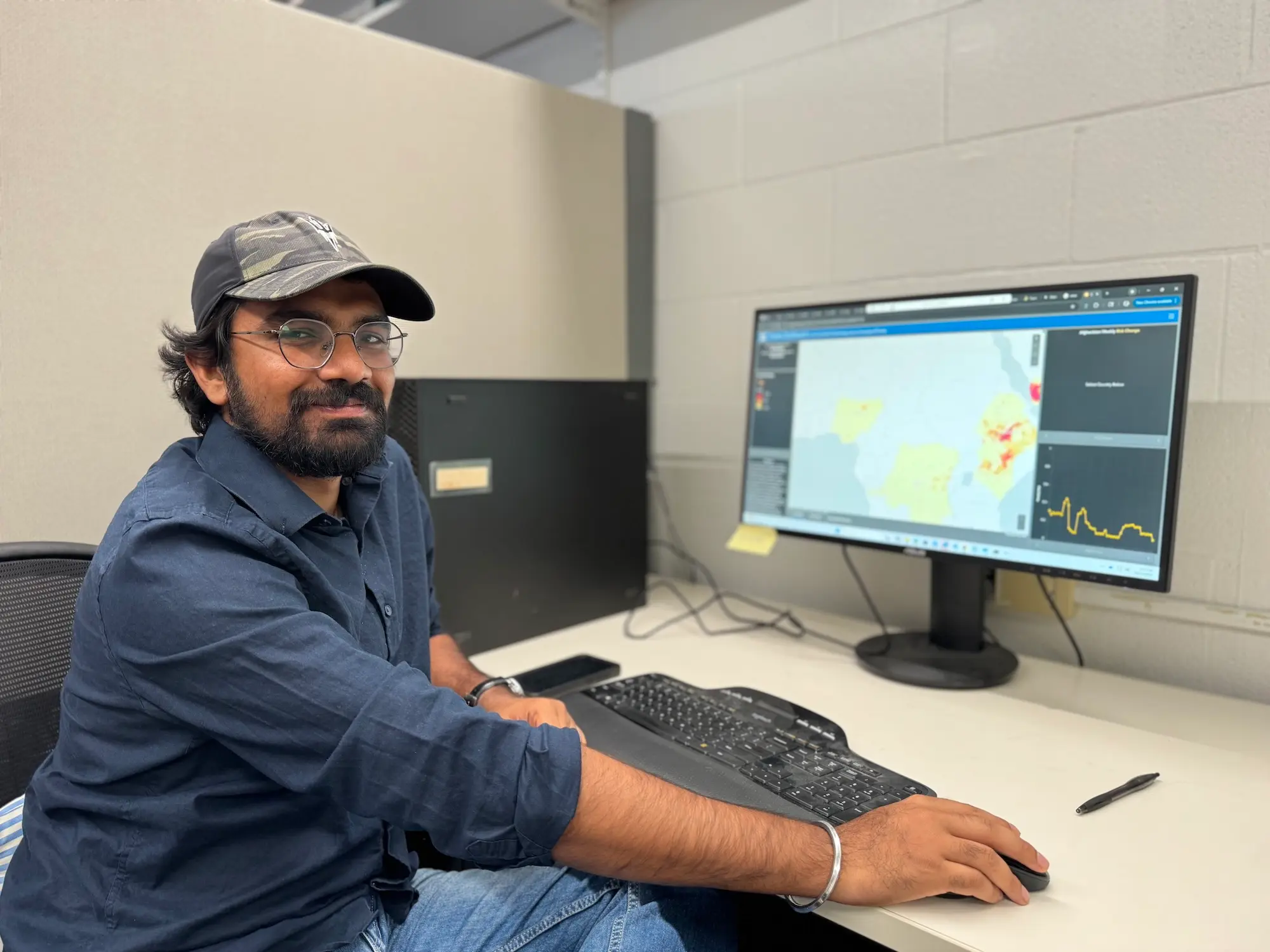 A man in a baseball hat sits in front of a computer monitor showing spacial data