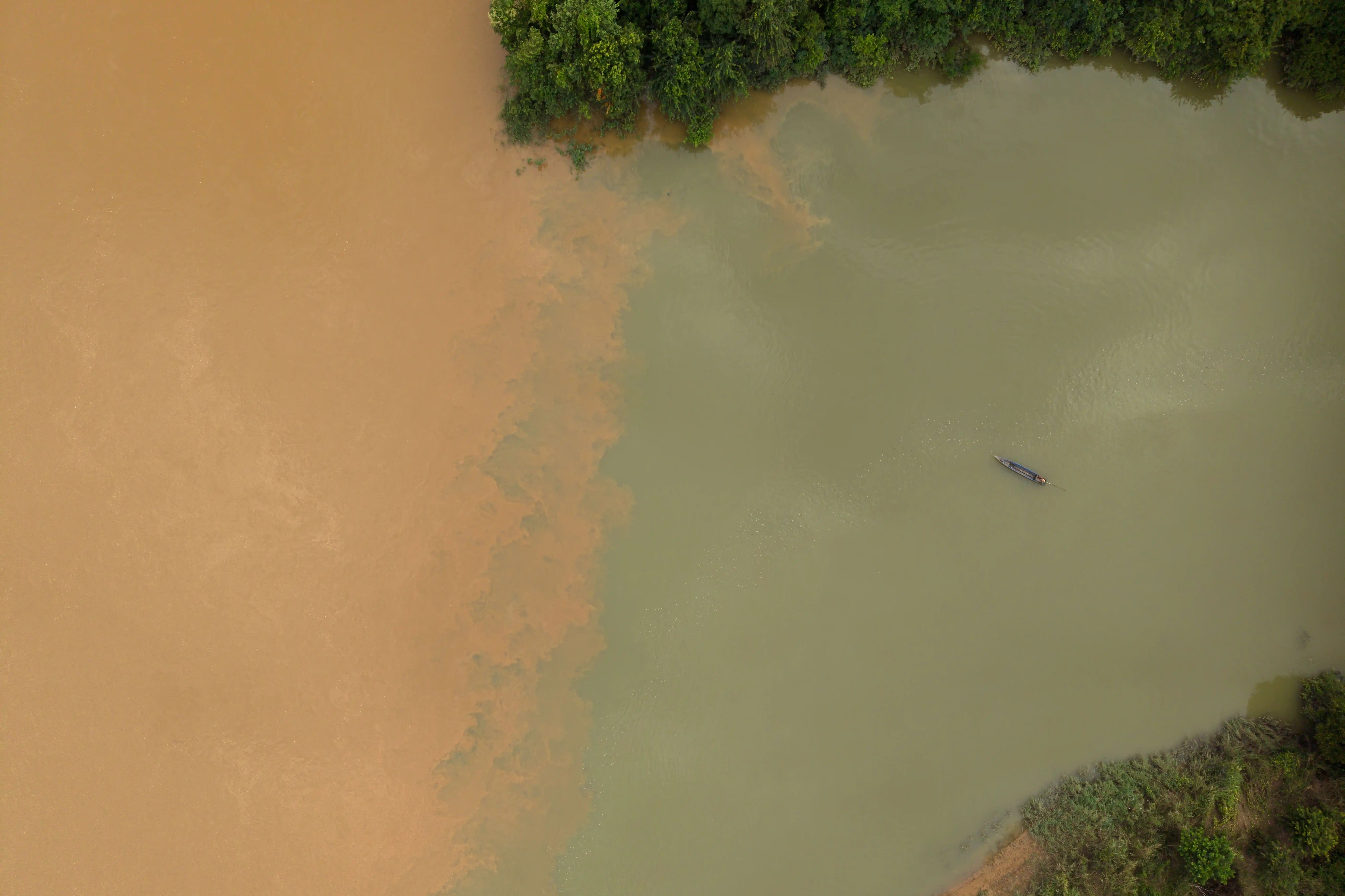 A fisher lays nets on the O’Ta Bouk River, just a few hundred meters from the O’Ta Bouk-Sesan confluence. Communities living along the river’s banks told Mongabay that the O’Ta Bouk no longer follows a seasonal color change. Instead, they said, it’s turned “muddy” all-year-round. Photo by Andy Ball/Mongabay.