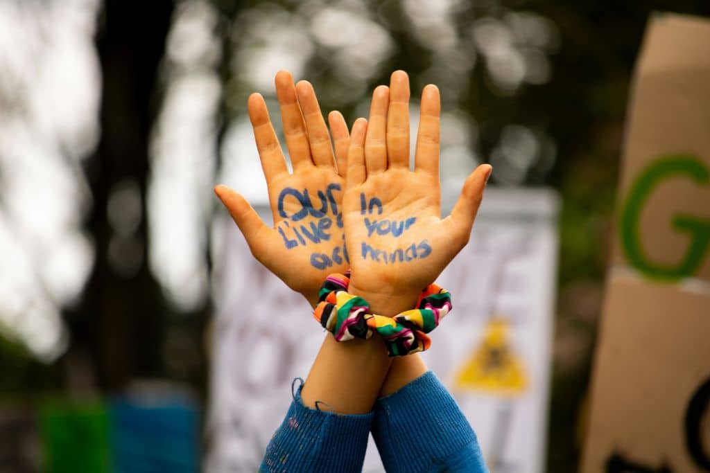 Raised hands with 'Our lives are in your hands' written across the palms.