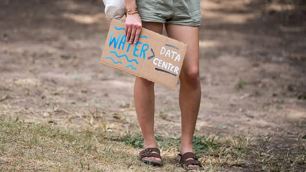 Lower half of a woman carrying a sign that reads water data centers